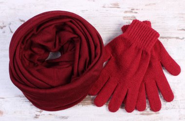 Pair of woolen gloves and shawl for woman on old wooden background