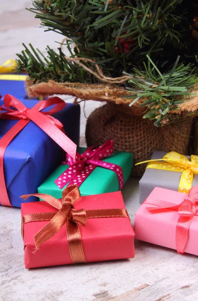 Wrapped colorful gifts for Christmas with christmas tree on old white plank — Stock Photo, Image