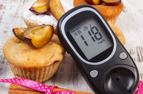 Glucometer, muffins with plums and cinnamon sticks on wooden background, diabetes and delicious dessert — Stock Photo, Image