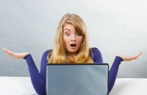 Испуганная женщина пожимает плечами и смотрит на ноутбук, проблемы с компьютером — стоковое фото