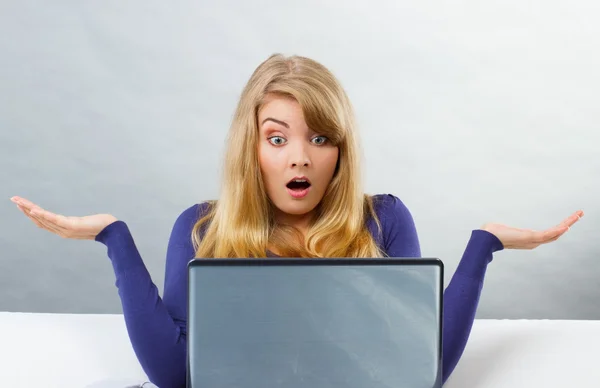 Scared woman shrugging shoulders and looking at laptop, computer problem — Stok fotoğraf