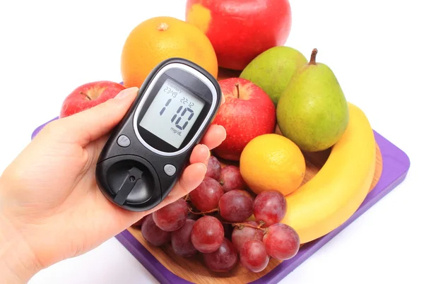 Mano de mujer con glucómetro y frutas frescas — Foto de Stock