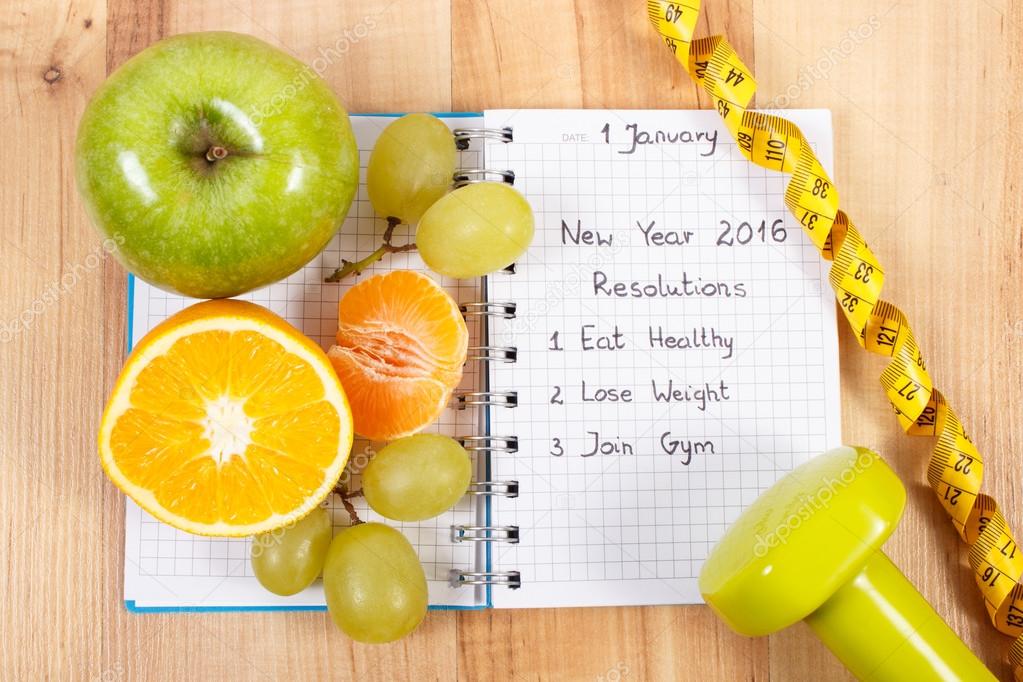 New years resolutions written in notebook and fruits, dumbbells with centimeter