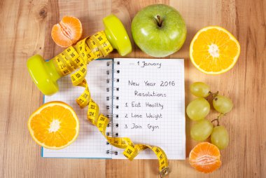 New years resolutions written in notebook and dumbbells with centimeter