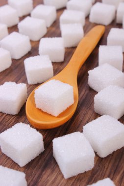 Küp şeker ahşap arka plan üzerinde tahta kaşıkla