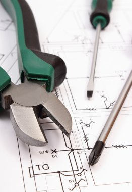 Metal pliers and screwdriver on electrical construction drawing of house