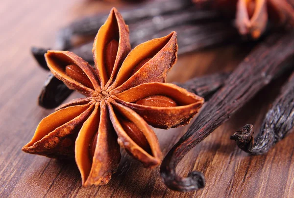 Closeup de anis estrelado e baunilha perfumada na prancha de superfície de madeira — Fotografia de Stock