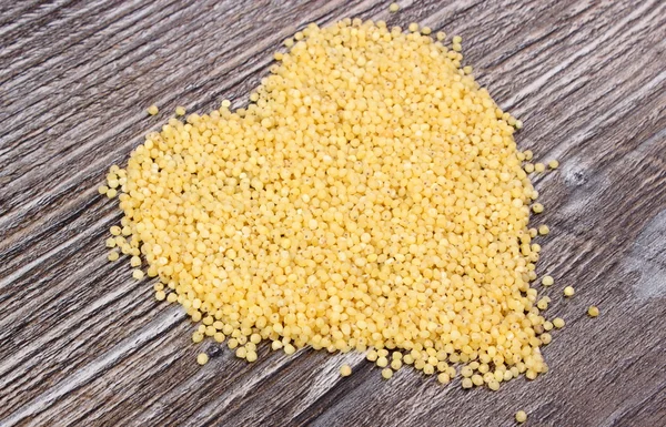 Heart of millet groats on wooden background — Stock Photo, Image