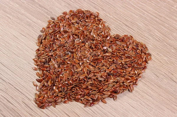 Corazón de linaza sobre fondo de madera — Foto de Stock