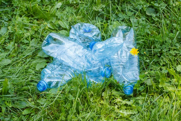 Garrafas de plástico de água mineral na grama no parque, lixo do meio ambiente — Fotografia de Stock