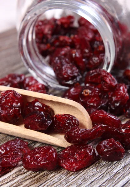 Cranberries spilling out of glass jar on wooden table — Stock Photo, Image