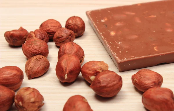 Voedzaam chocolade en hazelnoten op houten tafel — Stockfoto