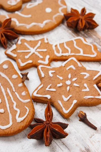 Fresh baked decorated gingerbread with spices on old wooden background, christmas time — Stock Photo, Image