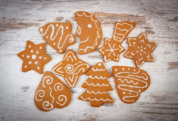 Fresh baked decorated gingerbread on old wooden background, christmas time — Stock Photo, Image
