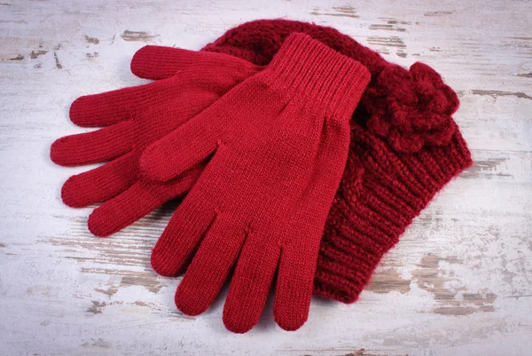 Pair of woolen gloves and cap for woman on old wooden background — Stock Photo, Image