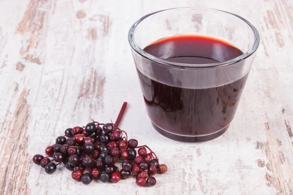 Bunch of fresh elderberry with juice on old wooden background, healthy nutrition — Stock Photo, Image