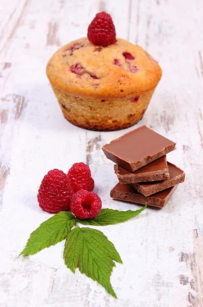 Свежие кексы с малиной и шоколадом на деревянном фоне, вкусный десерт — стоковое фото