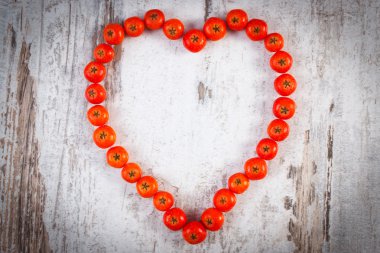 Ahşap arka plan üzerinde kırmızı sonbahar rowan kalbinde