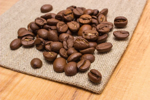 Altura de grãos de café em tela de juta na mesa — Fotografia de Stock