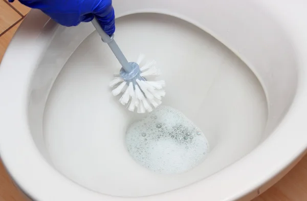 Hand einer Frau in blauem Handschuh reinigt Toilettenschüssel — Stockfoto