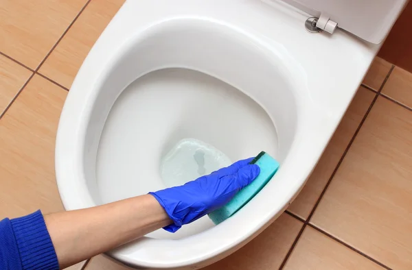 Mão de mulher em luva azul limpeza vaso sanitário — Fotografia de Stock