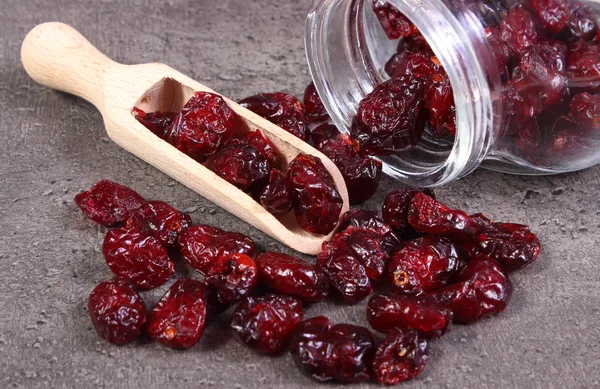 Cranberries spilling out of glass jar on concrete — Stock Photo, Image