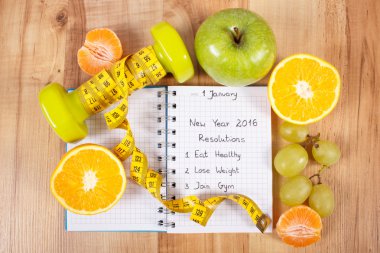 New years resolutions written in notebook and dumbbells with centimeter