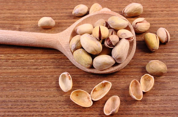 Orzechy pistacjowe z łyżką na drewnianym stole, zdrowe jedzenie — Zdjęcie stockowe