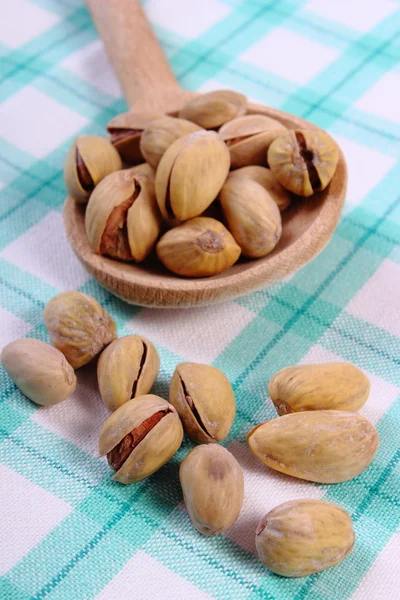 Pistachio nuts with spoon on checkered tablecloth, healthy eating — Stock Photo, Image