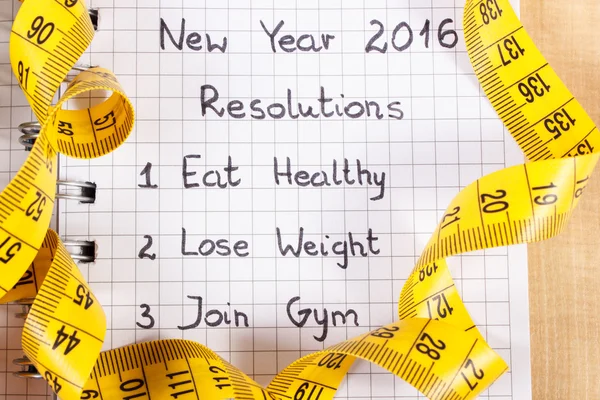 New years resolutions written in notebook and tape measure — Stock Photo, Image