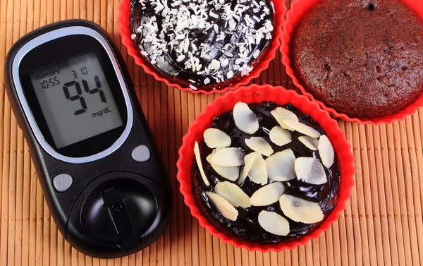 Glukometer und Schokoladenmuffins in roten Tassen — Stockfoto
