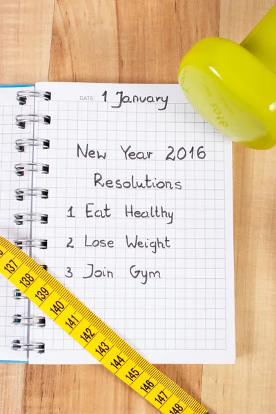 New years resolutions written in notebook and dumbbells with centimeter — Zdjęcie stockowe