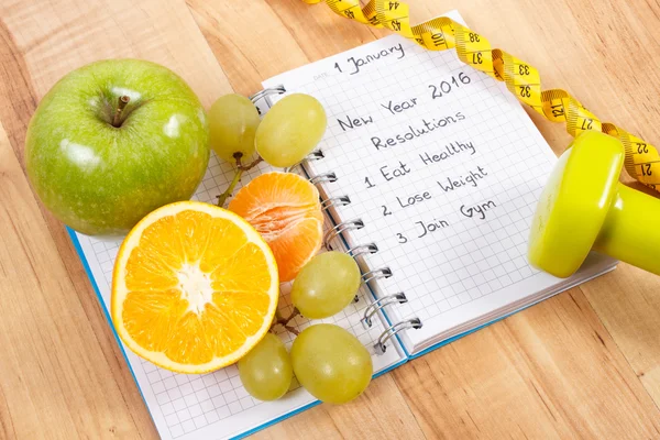 Resoluciones de año nuevo escritas en cuaderno y frutas, mancuernas con centímetro — Foto de Stock