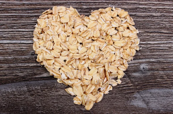 Corazón de copos de avena sobre fondo de madera — Foto de Stock