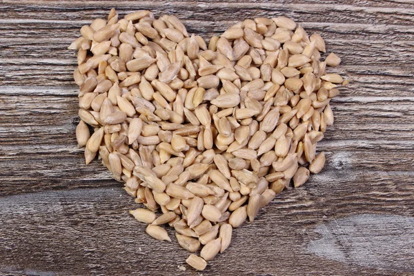 Heart of sunflower seeds on wooden background — Stock Photo, Image
