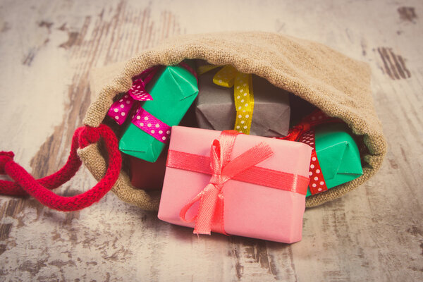 Винтажное фото, завернутые подарки в джутовую сумку на Рождество или другой праздник
