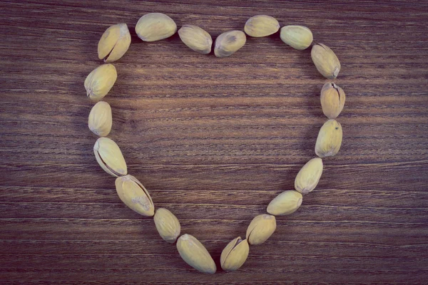 Vintage foto, hjärtat av pistagenötter på träbord, hälsosamt ätande — Stockfoto