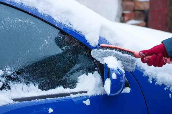 Hand der Frau mit Pinsel und Schnee von Auto, Windschutzscheibe und Spiegel entfernen — Stockfoto