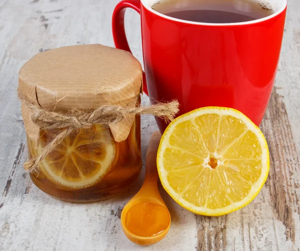 Лимон с медом и чашкой чая на деревянном столе, здоровое питание — стоковое фото