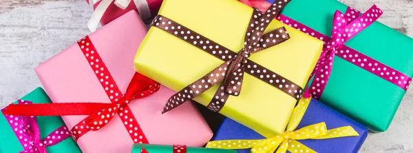 Verpackte bunte Geschenke für Weihnachten oder andere Feierlichkeiten auf alten weißen Planken — Stockfoto