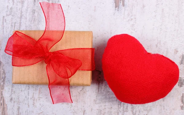 Wrapped gift for Valentines day and red heart on old wooden table — Stock Photo, Image