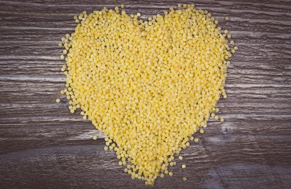 Vintage photo, Heart of millet groats on wooden background — ストック写真