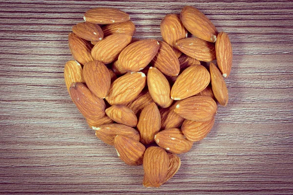 Vintage photo, Heart of almonds on wooden background — Stock fotografie