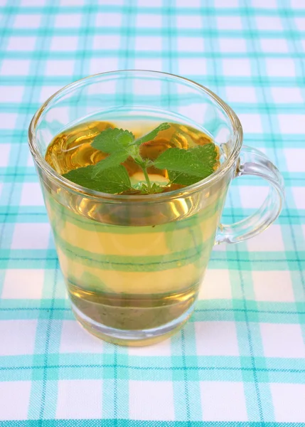 Fresh lemon balm and glass of herbal drink on tablecloth — Stockfoto