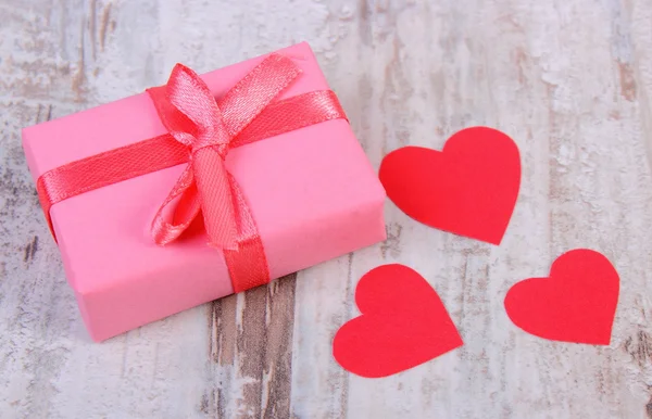 Wrapped gift for birthday, valentine or other celebration and red hearts — Stock Photo, Image