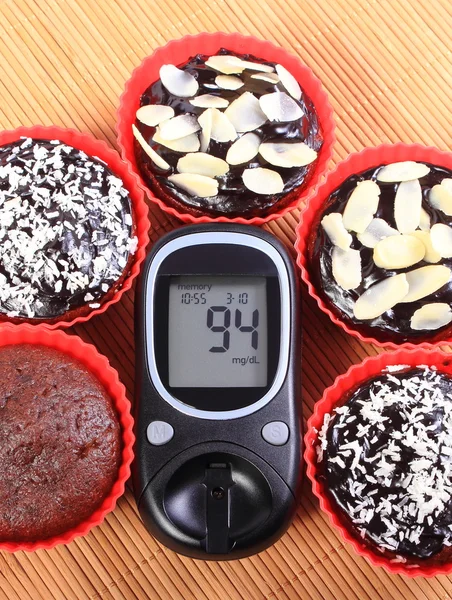 Medidor de glucosa y magdalenas de chocolate en tazas rojas — Foto de Stock