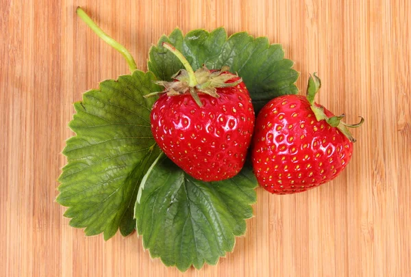 Strawberry with leaves on wooden surface — Stock Photo, Image