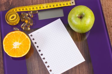 Digital scale with tape measure, tablets and fresh fruits, slimming concept
