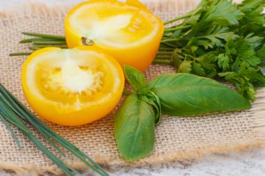 Yeşil maydanoz ve fesleğen güneşli bahçesinde jüt tuval üzerine sarı domates