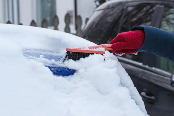 Mano della donna con pennello e rimuovere la neve da auto e parabrezza — Foto Stock